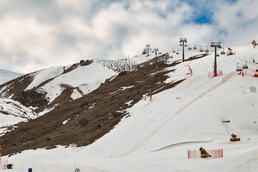 Een met sneeuw bedekte piste met skiliften en een berg op de achtergrond. 4