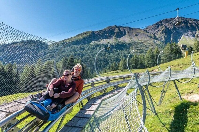 Iemand bevindt zich op een zipline, met een bergachtig landschap op de achtergrond. 2