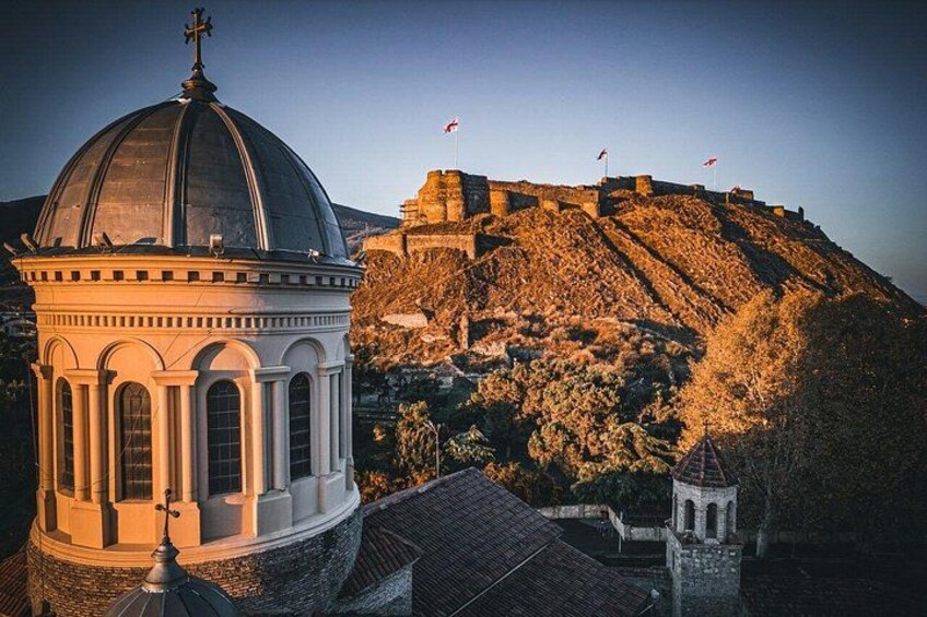 A historical building with a dome, a hill with flags, and a small tower. 3