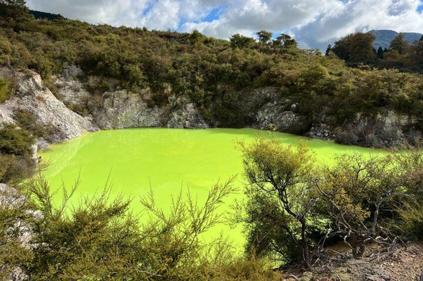 Un lago verde circondato da alberi e terreno roccioso. 2