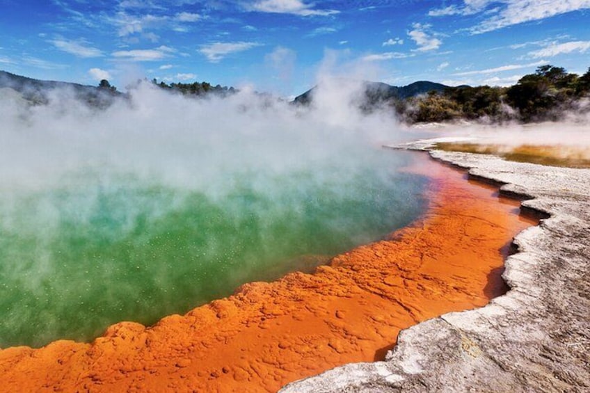Un'area geotermica con sorgenti termali colorate e vapore che sale dal terreno. 1