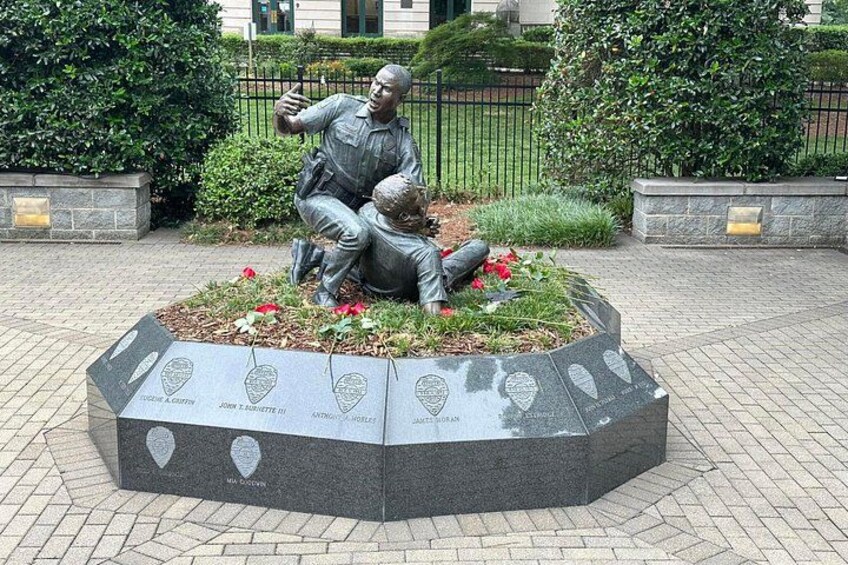 En statue af to personer i en have, med indgraverede navne på soklen. 3