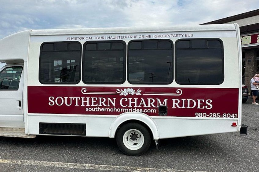 Un autobús blanco con detalles color borgoña y el texto 'SOUTHERN CHARM RIDES' y una dirección web. 3