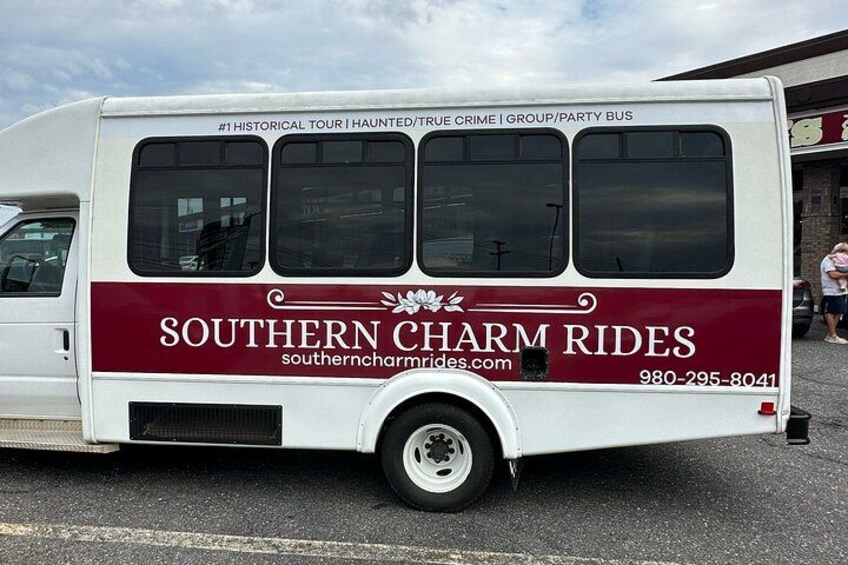 Een witte touringbus met de branding 'Southern Charm Rides' en contactgegevens. 3