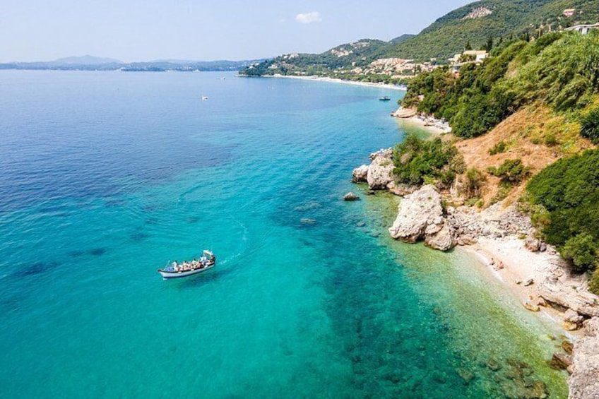 A boat on a turquoise sea, a rocky coastline, and a hilly landscape in the background. 4