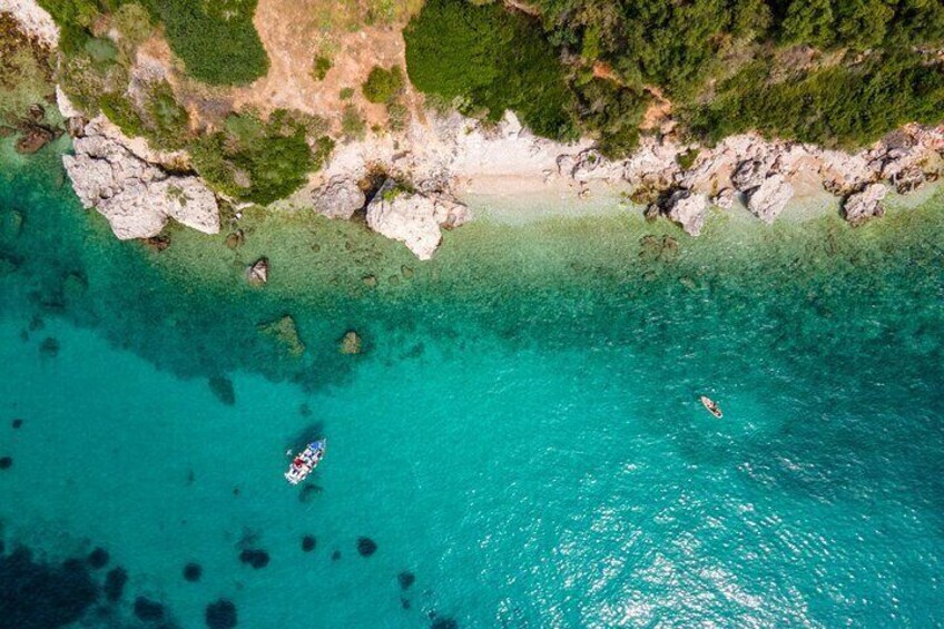 An aerial view of a turquoise coastal area with rocky outcrops and clear waters. 4