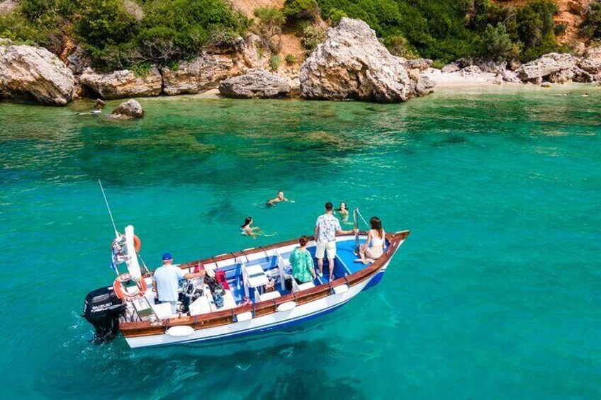 A boat with people swimming and sitting in clear turquoise water. 5
