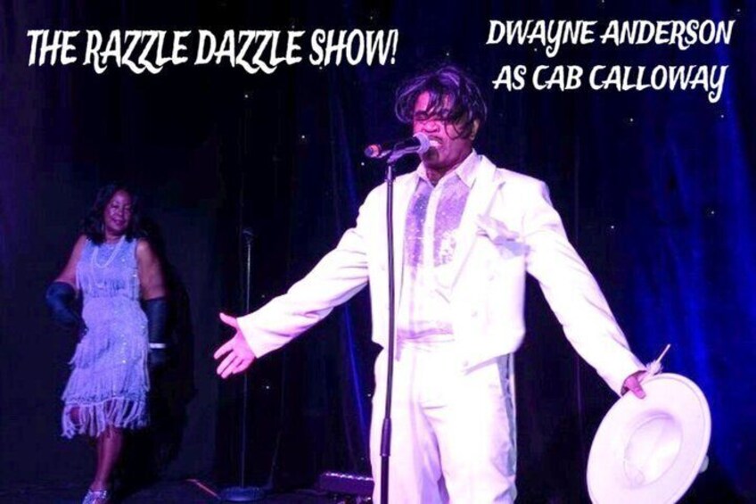 Dwayne Anderson performing as Cab Calloway on stage with a microphone and a hat. 2