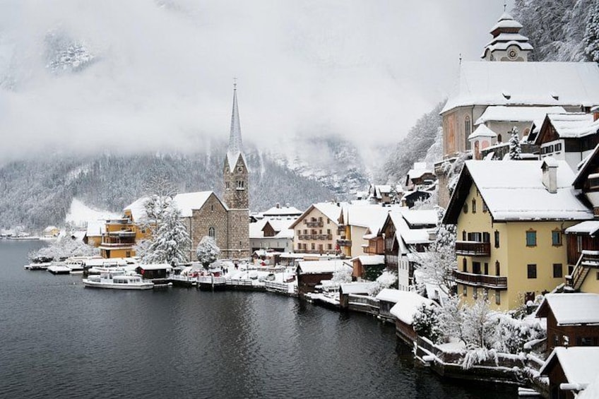 Een besneeuwd dorp met een kerk, boten en huizen aan een rivier. 2