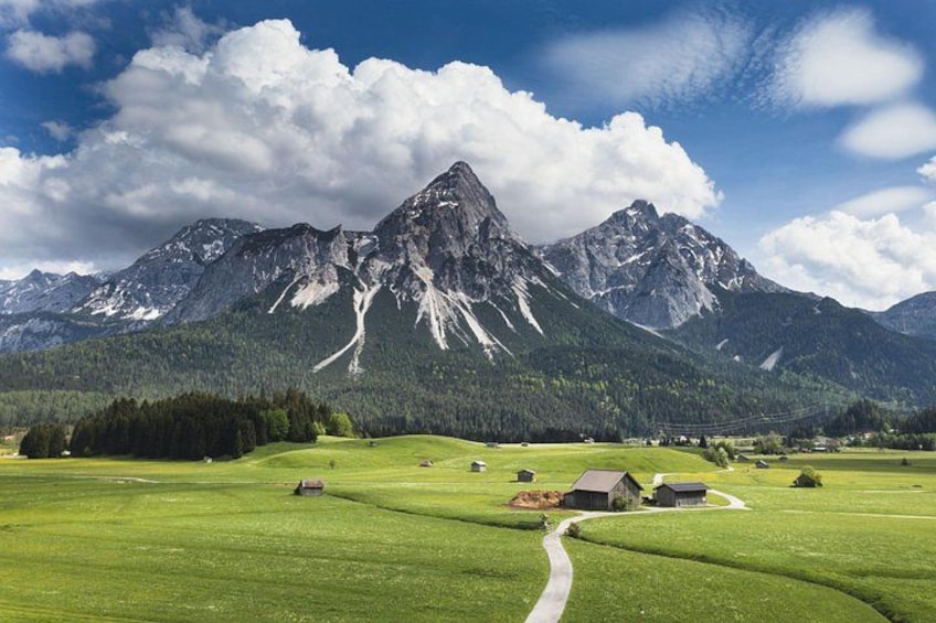 Een bergachtig landschap met een heldere lucht, groene velden en enkele gebouwen. 4