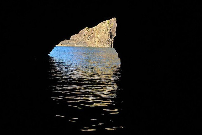 Entrada a una cueva con un acantilado rocoso y agua tranquila. 4