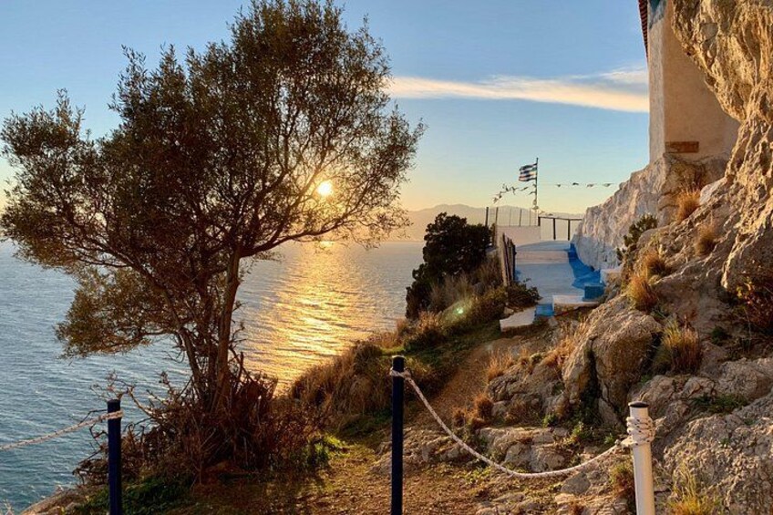 Eine Küstenlandschaft mit Baum, felsigem Gelände, einer Brücke und einer Flagge. 5