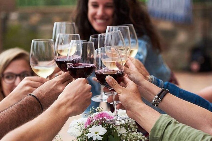Menschen stoßen mit Weingläsern an einem Tisch mit Blumen an. 3