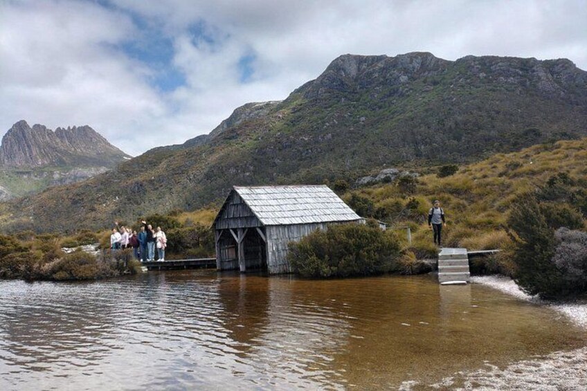 A wooden structure by a lake with mountains in the background. 4