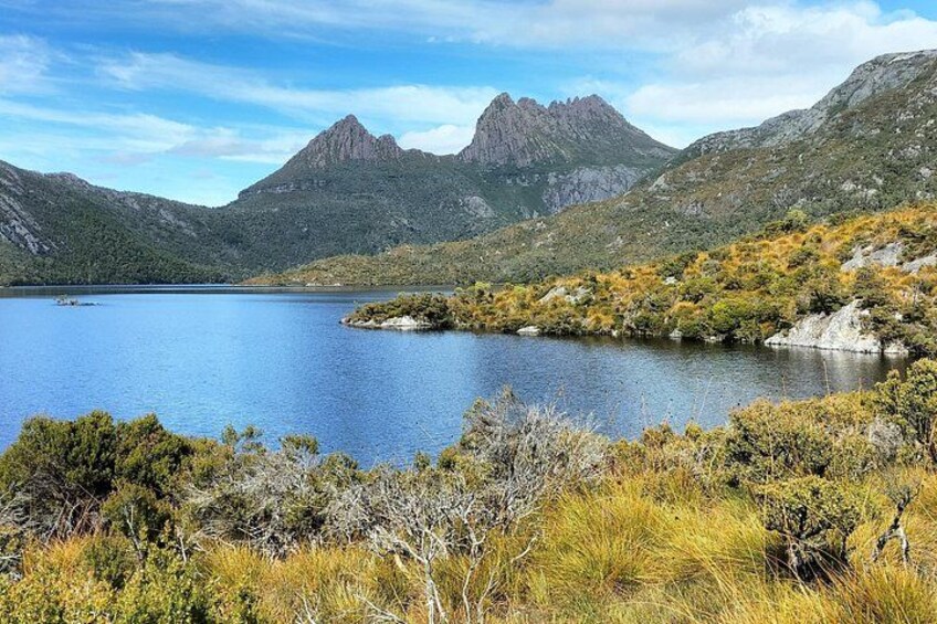 A lake surrounded by mountains, with a clear sky and sparse vegetation. 2