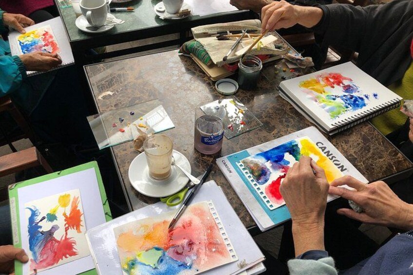 Een groep mensen die bezig is met schilderen, met diverse materialen op een tafel. 3