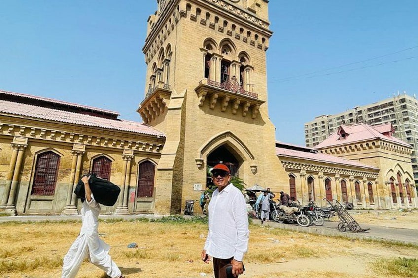 A person in white attire walking in front of a historic building with a tower. 4