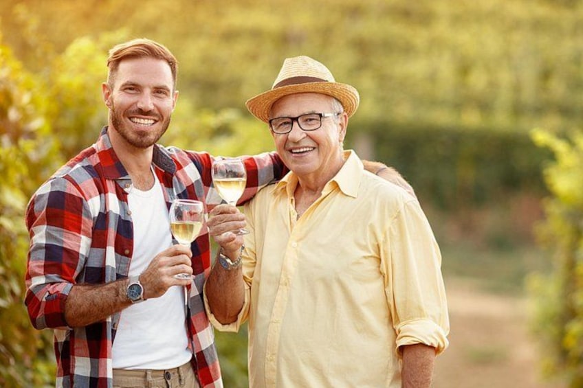 Two people holding wine glasses in a vineyard. 3