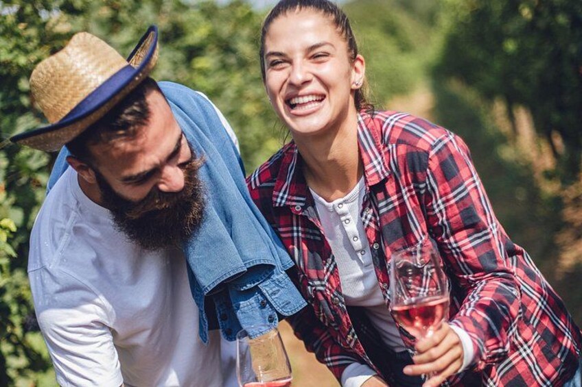 Two people outdoors, one wearing a straw hat and plaid shirt, the other in a plaid jacket, holding a glass. 5