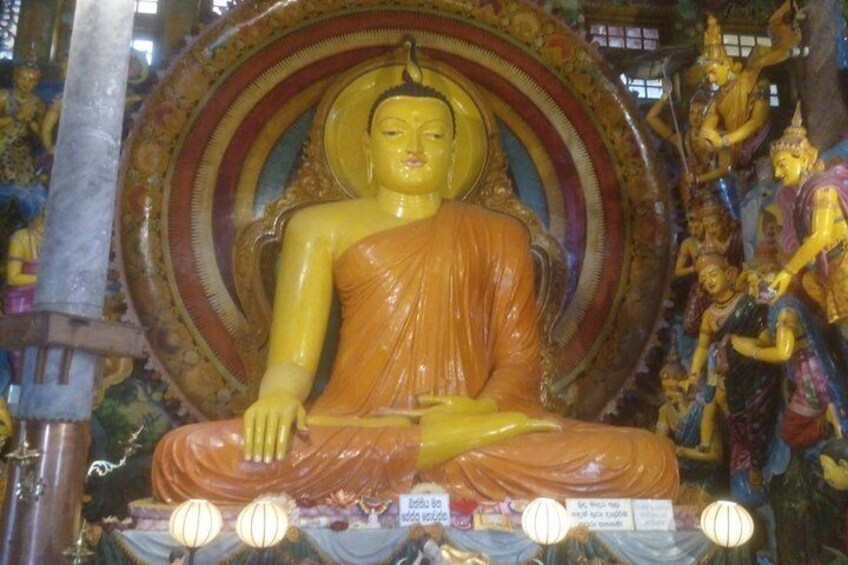 Eine gro ße sitzende Buddha-Statue in einem Tempel, mit aufwendigen Verzierungen und kleineren Statuen im Hintergrund. 4