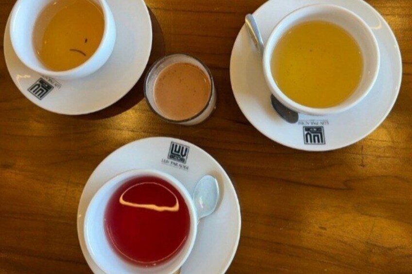 Ein Tisch mit vier Tassen Tee auf Untertassen, jede mit einem Logo. 3