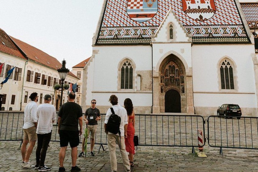 Eine Gruppe von Menschen steht vor einem historischen Gebäude mit Ziegeldach und großem Bogenportal. 2