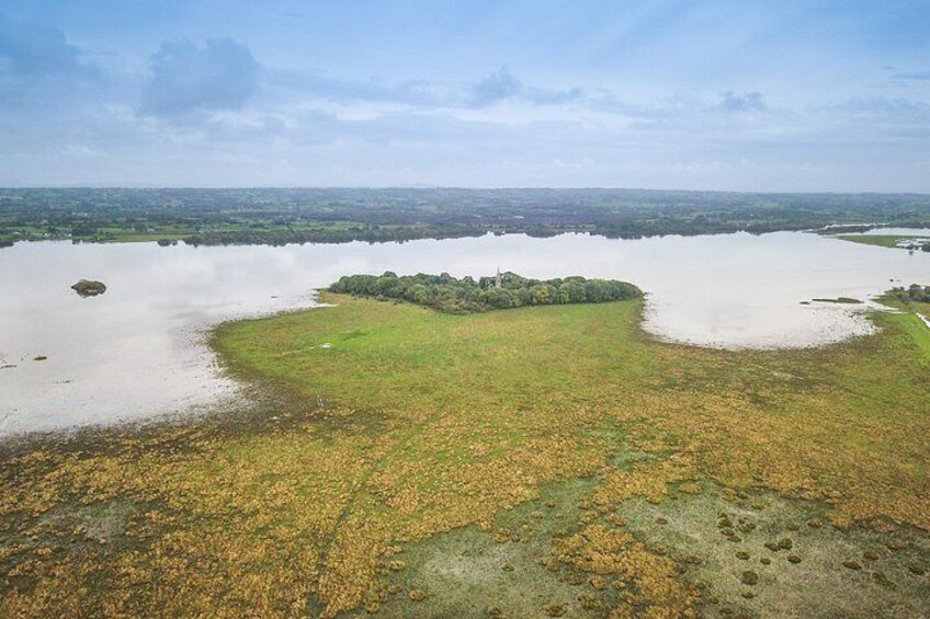 A large body of water with a small island in the center surrounded by grassy areas. 5