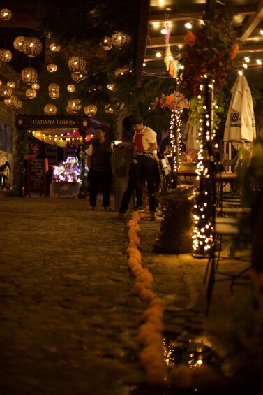Un marché de nuit en plein air, illuminé de lanternes suspendues, avec un chemin pavé de pierres. 2