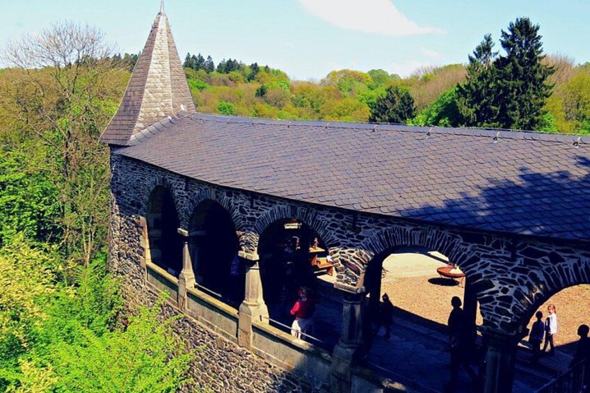 A stone building with a conical roof and arches, surrounded by greenery. 2