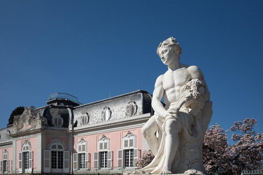 A large classical statue in front of a pink building with arched windows and a dome. 3