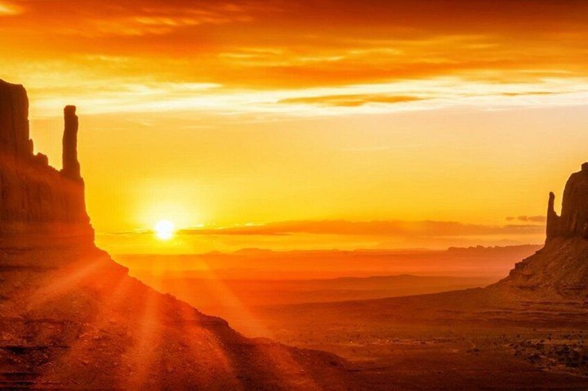 A sunset over a desert landscape with rock formations. 1