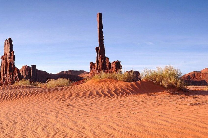 A desert landscape with red sand dunes and rock formations. 5