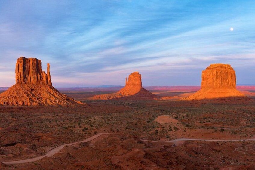 A desert landscape with three prominent rock formations under a twilight sky. 4