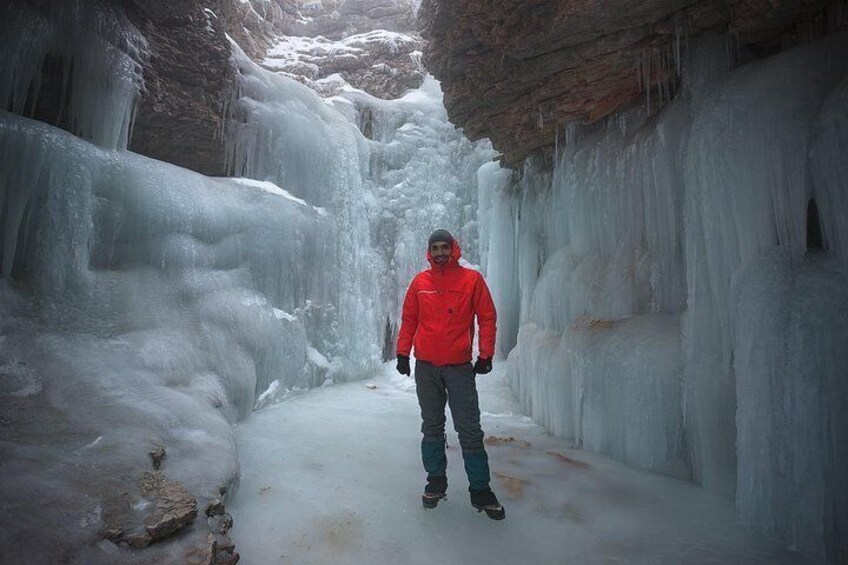 A person standing in a narrow, icy passageway with walls of ice. 5