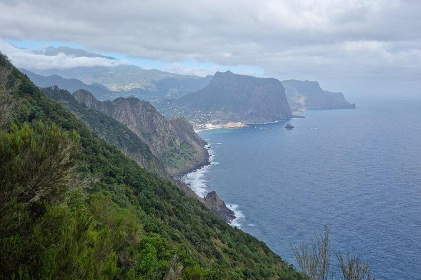 A coastal landscape with steep cliffs, a beach, and a clear view of the ocean. 3