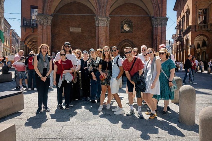 A group of people standing in front of a historic building with arches. 1