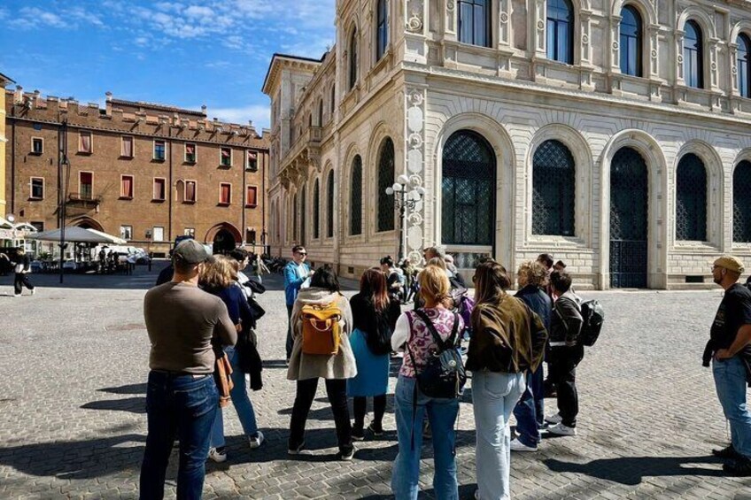 A group of people standing in a plaza with a historic building in the background. 2