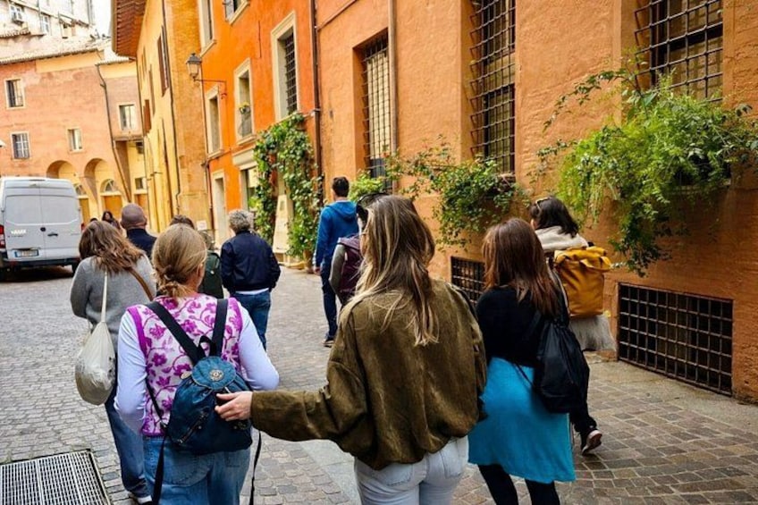 A group of people walking on a cobblestone street in a historic area with buildings featuring arched windows and brick walls. 4