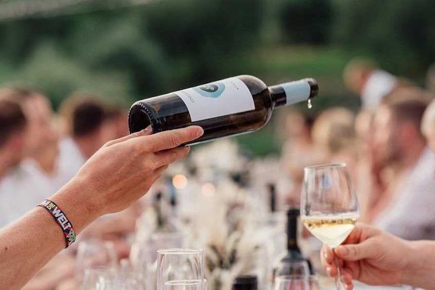 A person pouring wine into a glass at a social gathering. 4