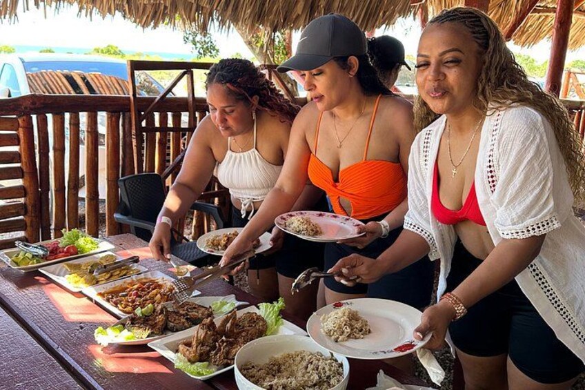Un groupe de personnes est réuni autour d’une table à l’extérieur, où sont servis différents plats. 3