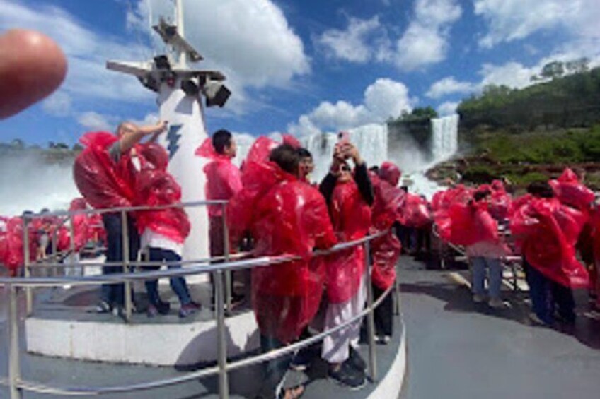 A group of people in red rain ponchos gathered around a fountain with a statue in the center. 5