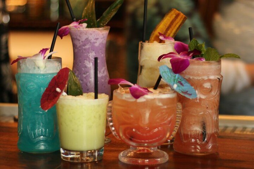 A variety of colorful cocktails with straws and garnishes on a bar counter. 2