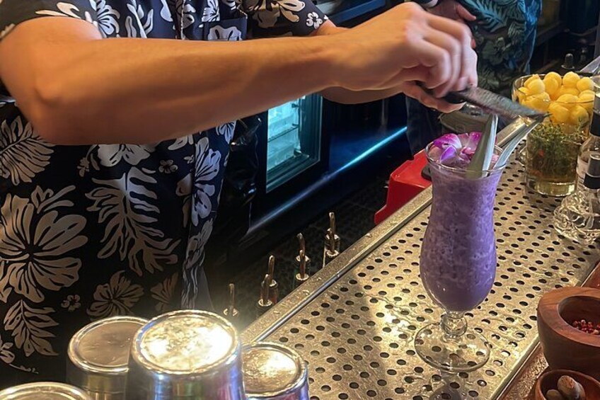 A bartender preparing a purple drink with a spoon. 3