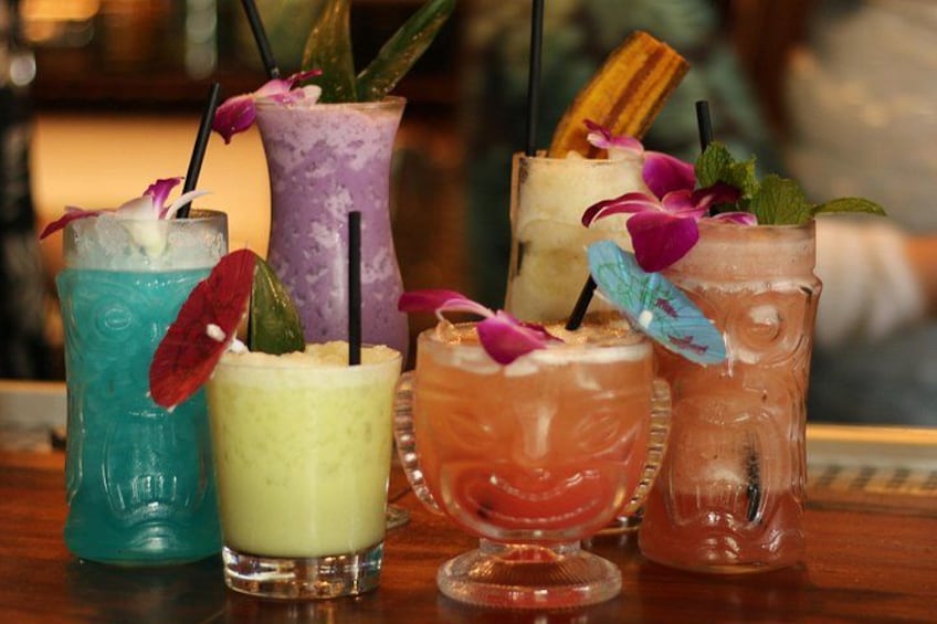 Une variété de cocktails colorés, servis avec des pailles et des décorations, sur le comptoir d’un bar. 2
