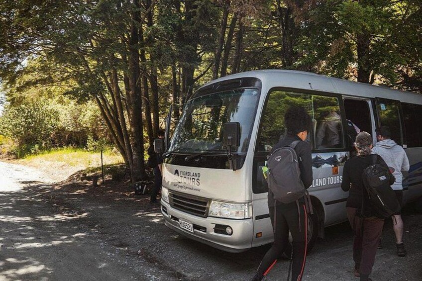 Un autobus turistico parcheggiato su una strada sterrata, circondato da alberi. 2