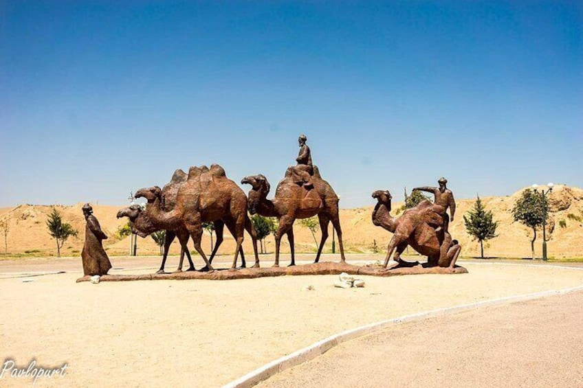 Paisaje desértico con una caravana de camellos y una persona guiándolos. 1