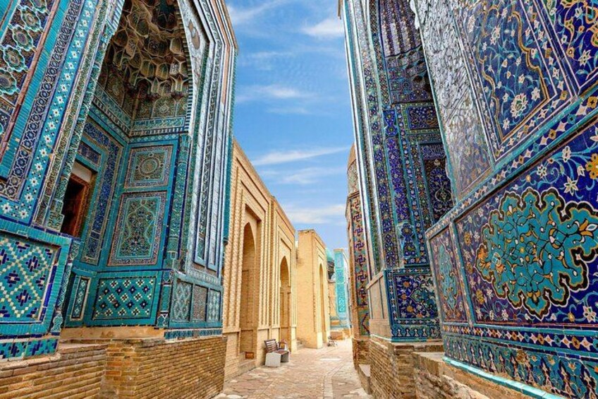 A narrow alleyway flanked by intricately decorated buildings with blue and turquoise tiles. 5