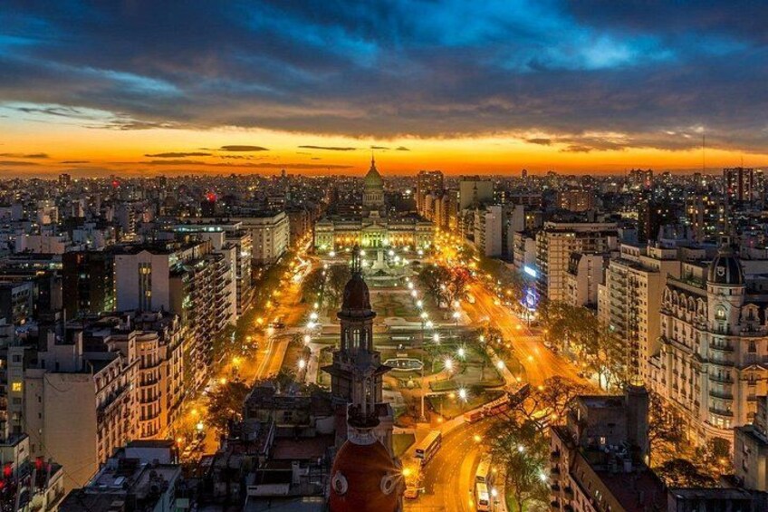 A cityscape at dusk with a prominent dome structure in the center, surrounded by illuminated streets and buildings. 3