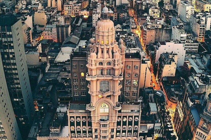 A cityscape with a prominent building featuring a large clock tower and intricate architectural details. 1