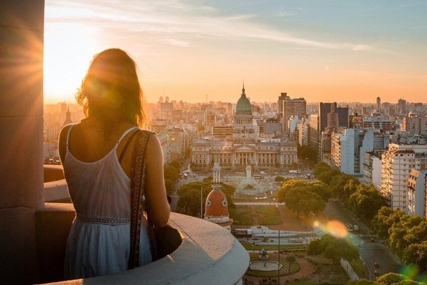 A woman overlooking a cityscape with a prominent domed building and modern high-rises. 5